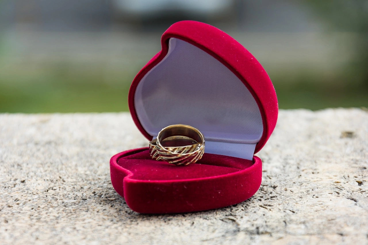 Two beautiful gold engagement rings placed on a opened heart shaped ring box