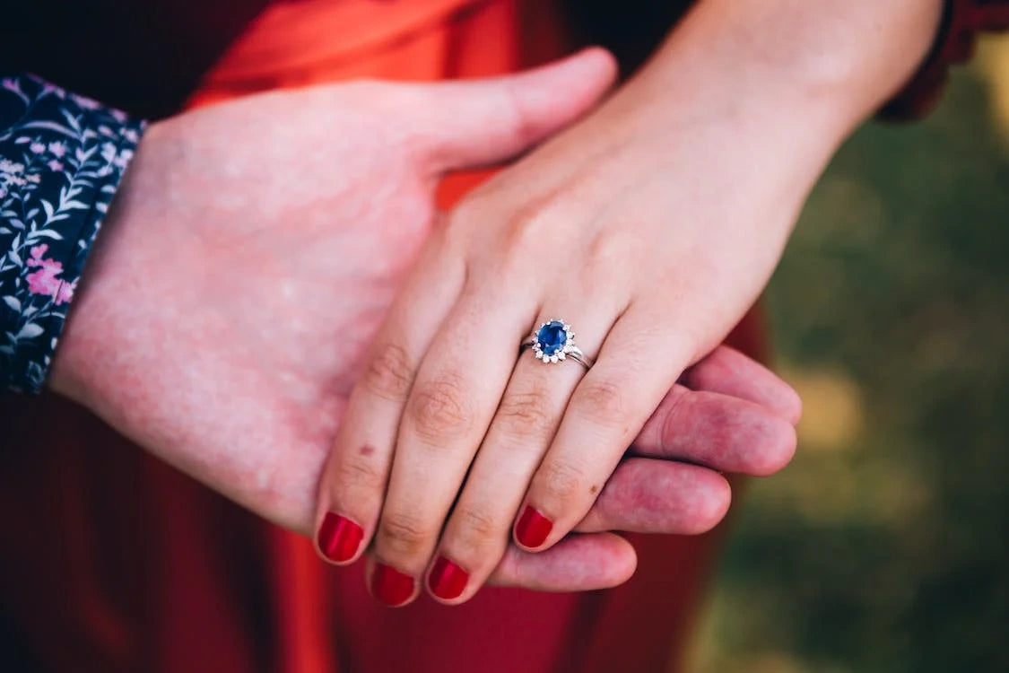 The couple intertwines their hands, showcasing the shimmering engagement ring