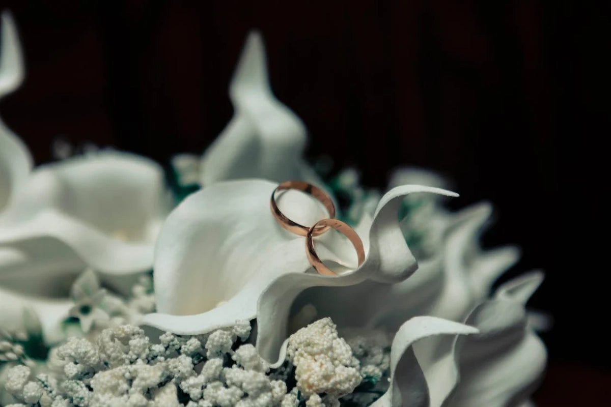 Two golden Engagement rings on a white flowers
