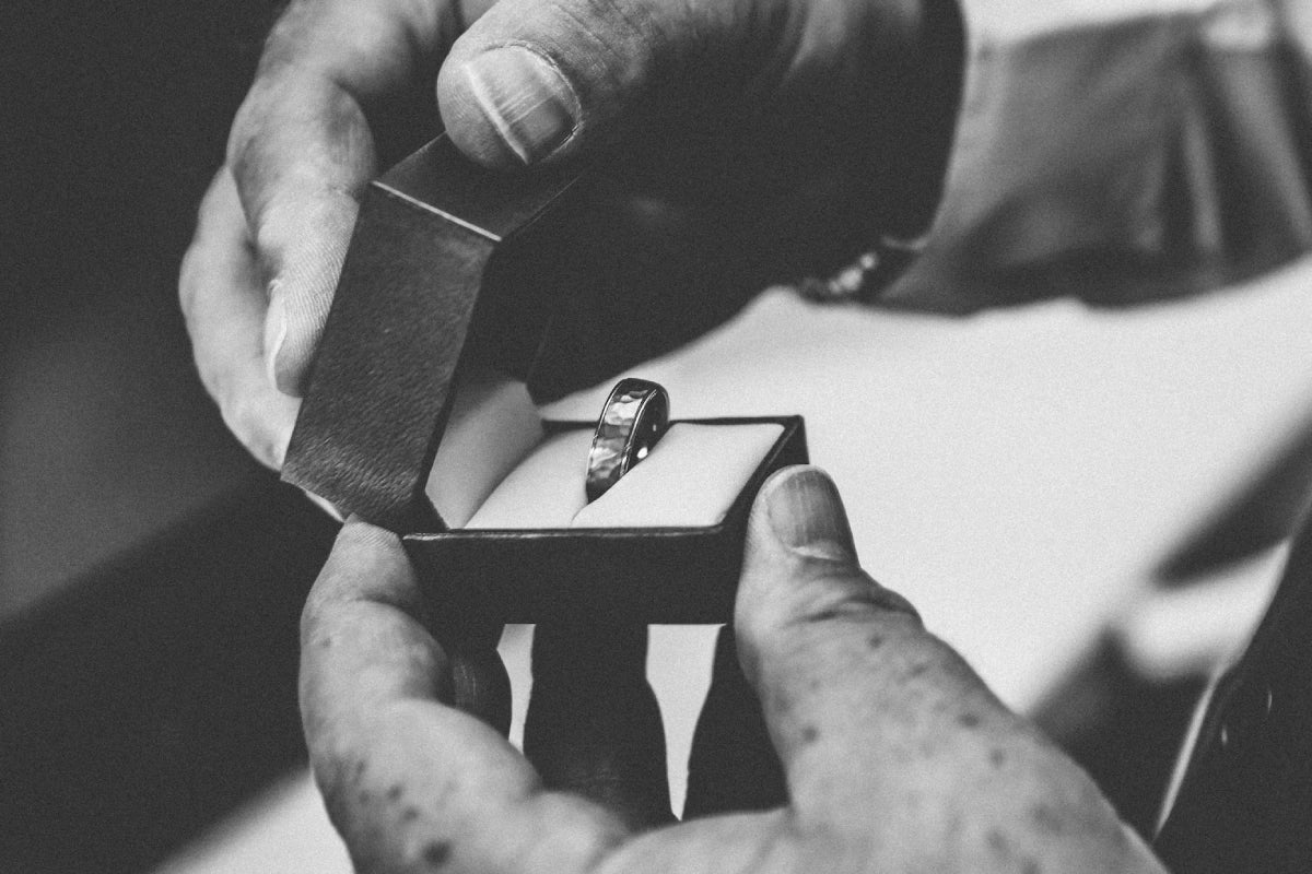 A person holding the silver-colored ring in opened box