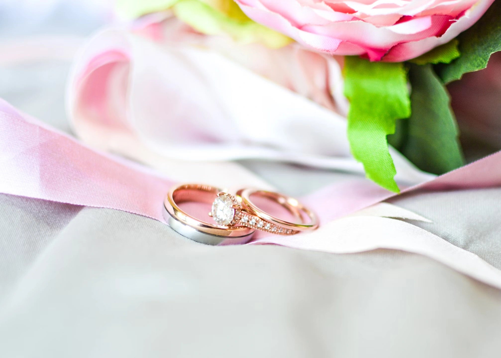 An engagement ring, radiant on pink cloth with a hint of rose, whispers timeless love amid delicate elegance