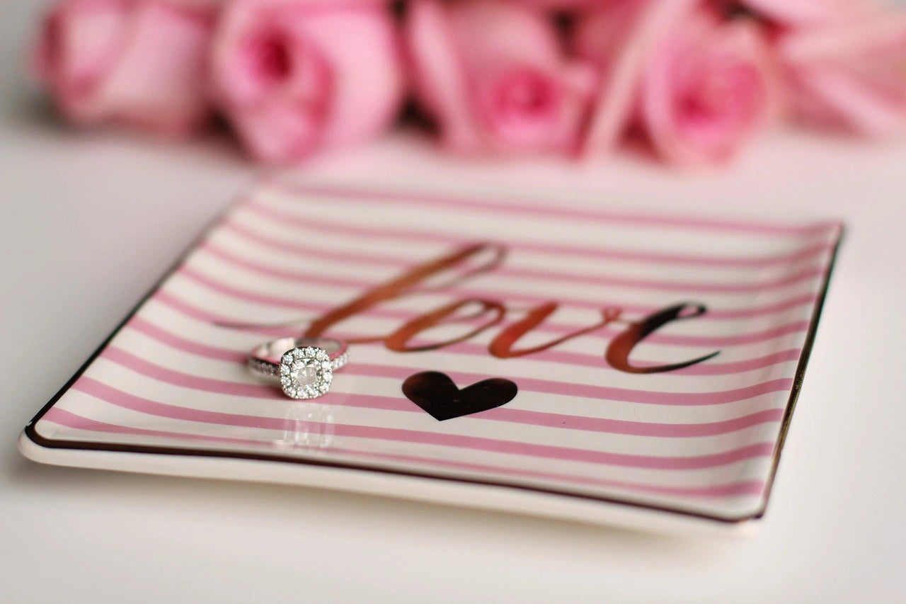 A symbol of everlasting commitment, an engagement ring delicately rests on a plate engraved with the word "love."