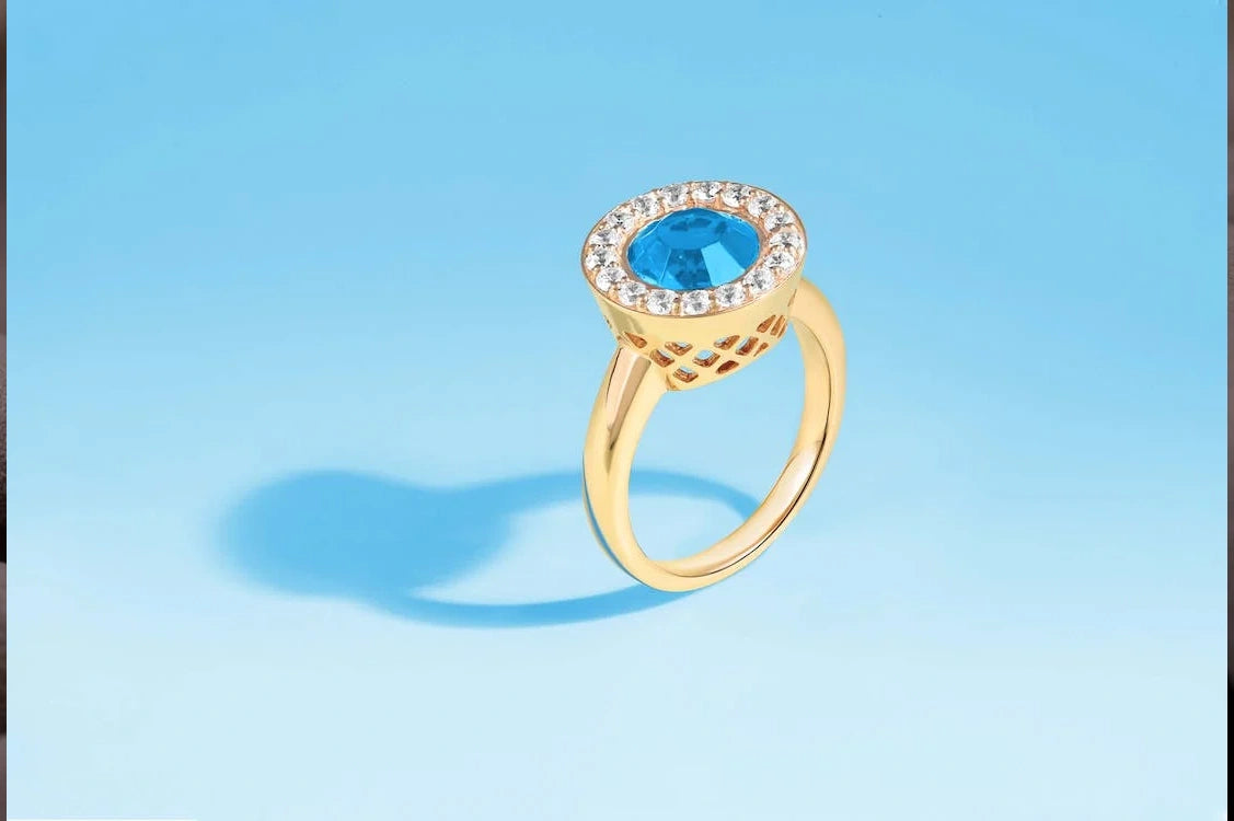 Gold and diamond ring with blue stone in the bluish background