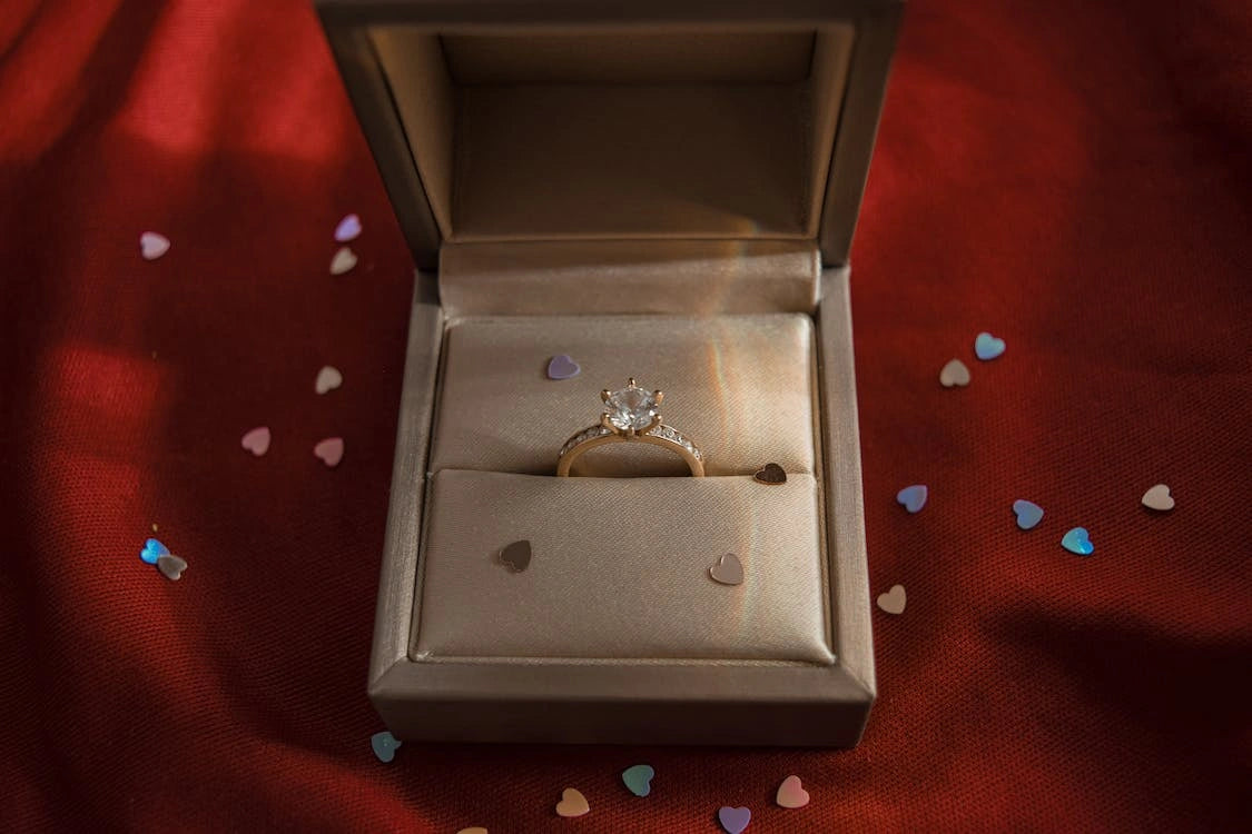 A golden engagement ring with white stone inside the opened case