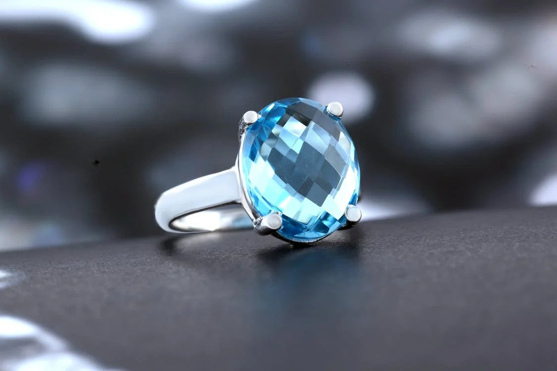 A stunning diamond ring with bluish stone on a black surface