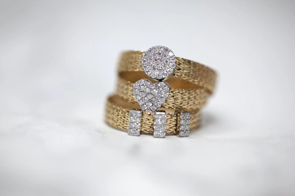 Three gold-colored studded rings on a white surface