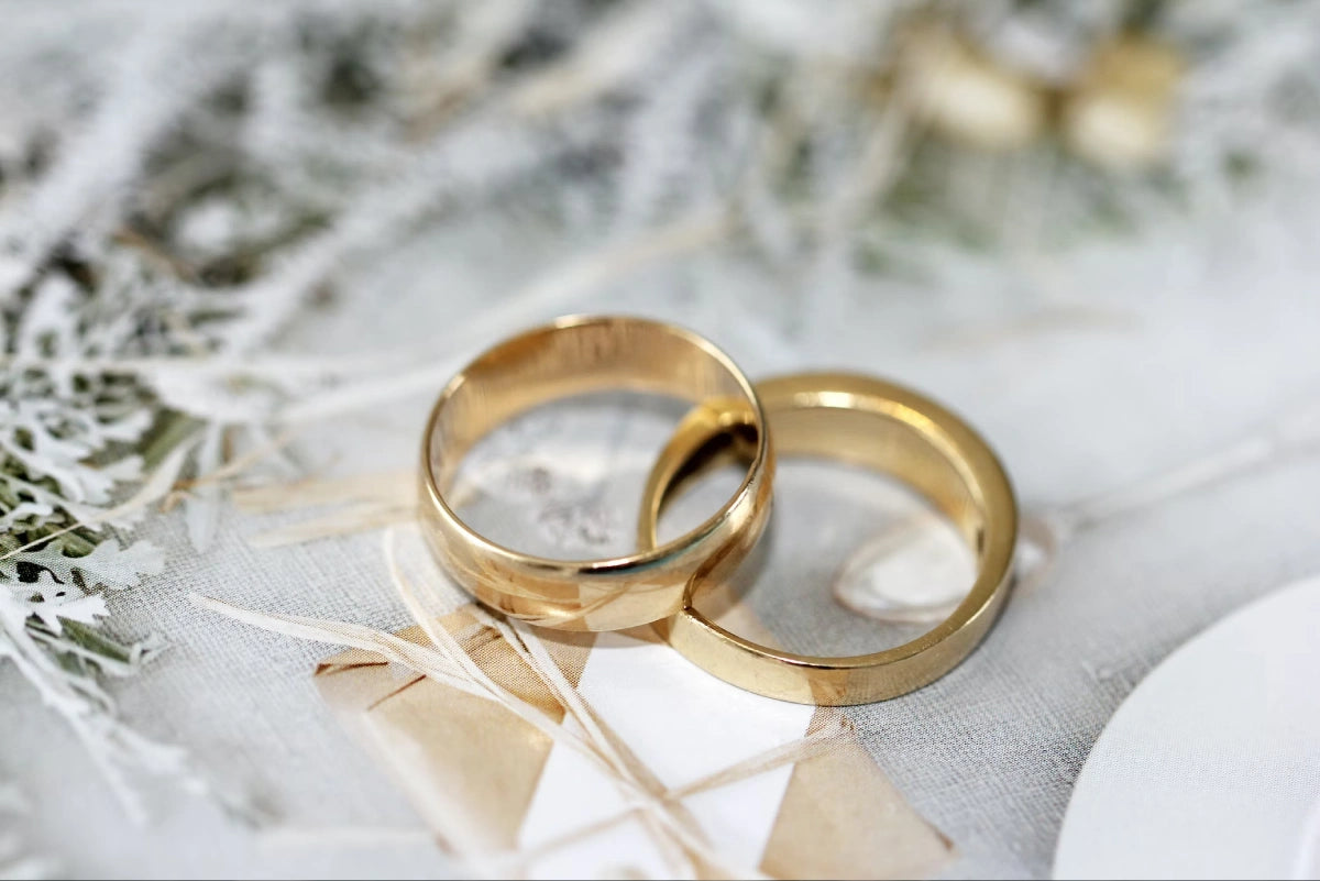 Two golden engagement rings are placed on the white surface