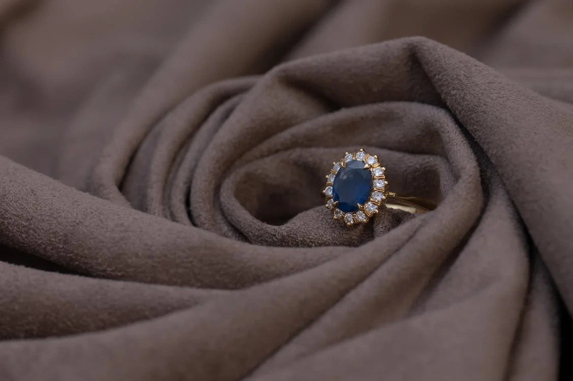 Gold ring with sapphire and diamond stones placed on the brown colored bedsheet