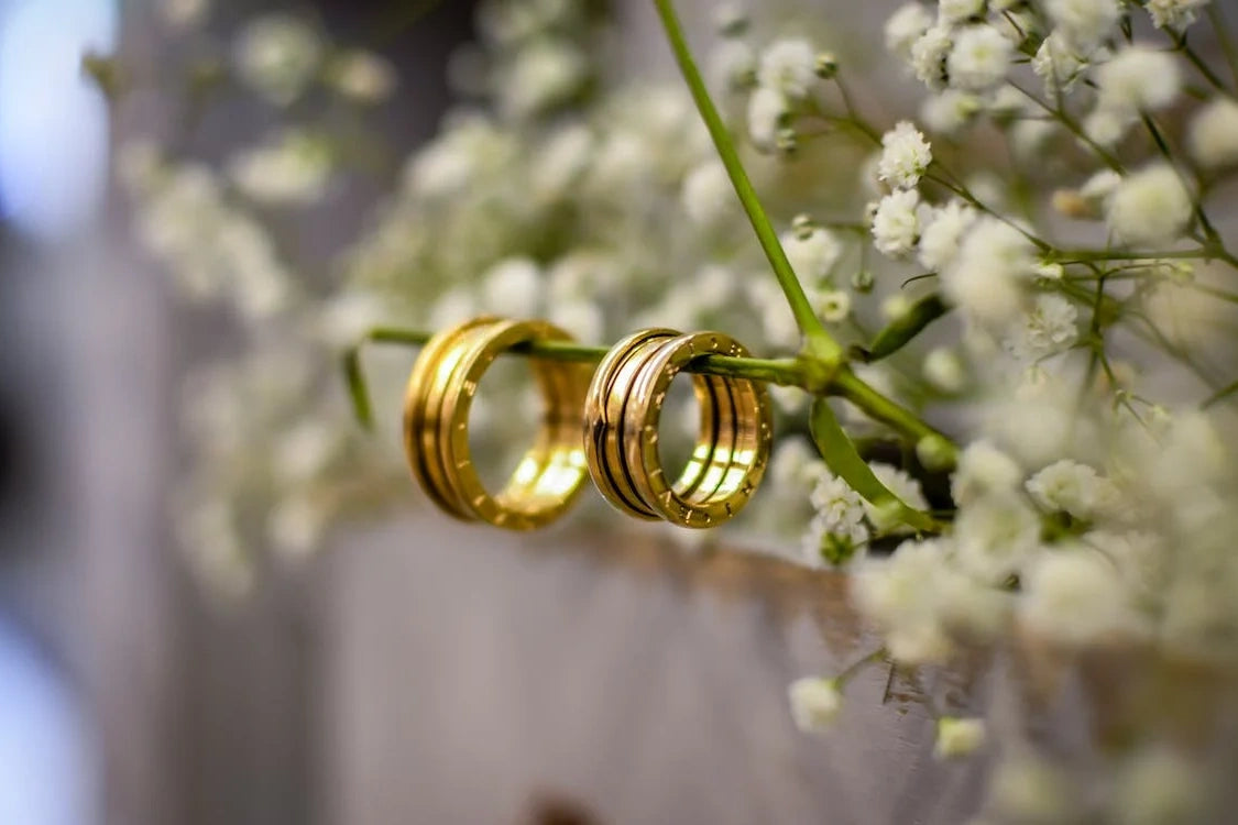 Two beautiful goldish engagement rings hanging on white flower stem