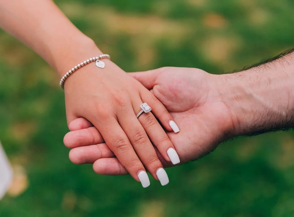 A couple holding hands with an engagement ring