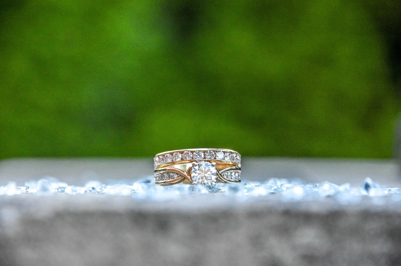 A gold and diamond engagement ring with greenary background