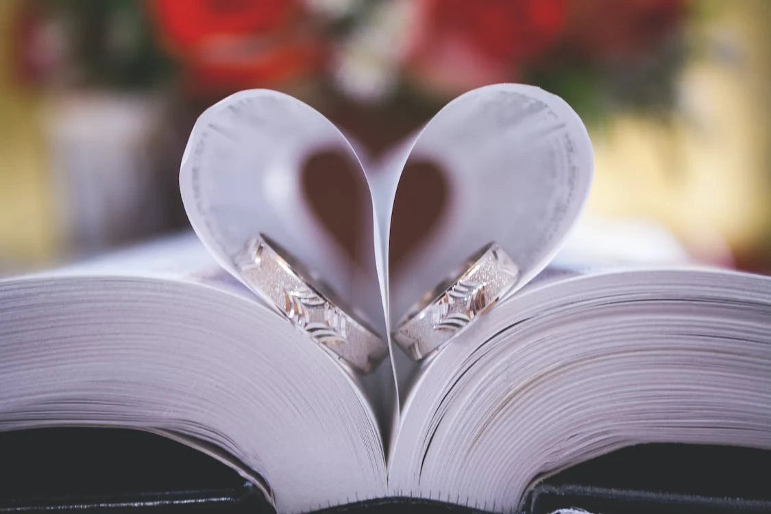 Two beautiful engagement rings are placed on the opened book with folded sheets