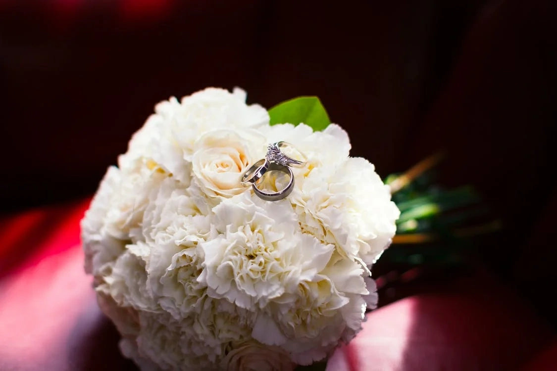 Wedding rings are placed on a beautiful white flowers bouquet