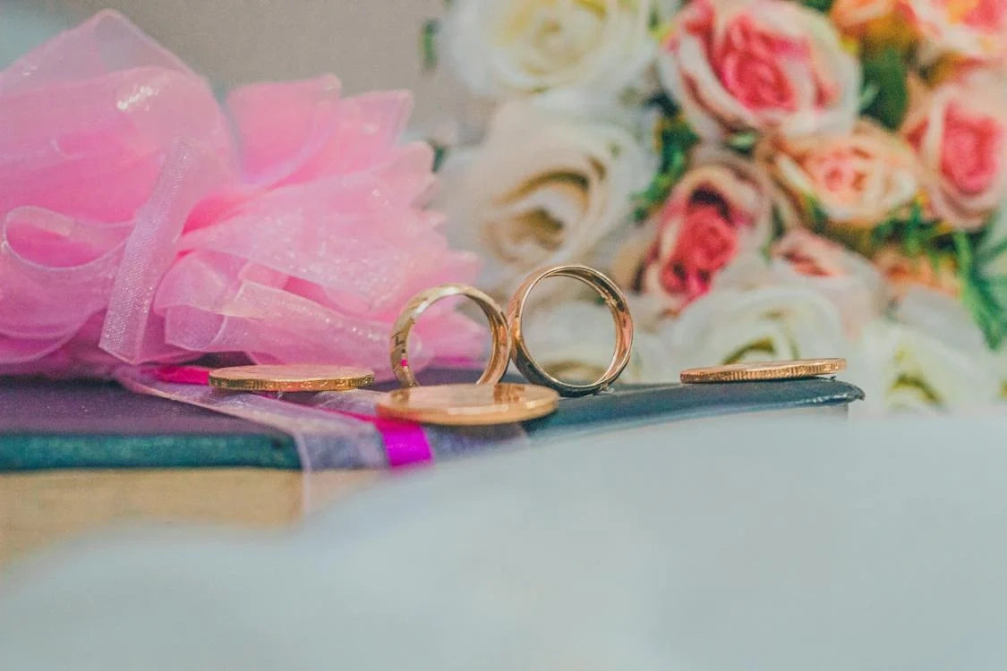 Two gold engagement rings placed with some flowers