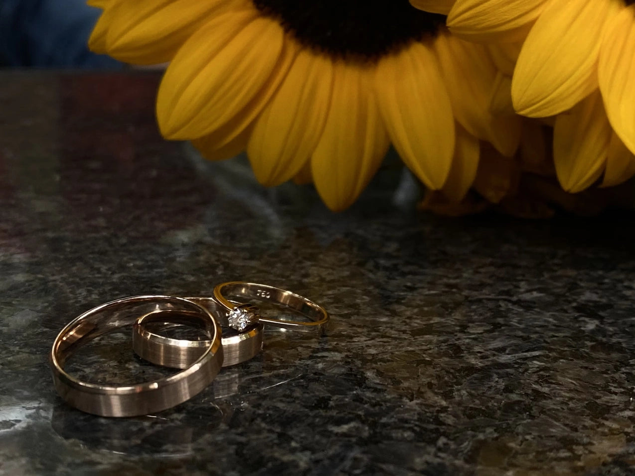 An engagement rings placed on the floor with some yellow flowers