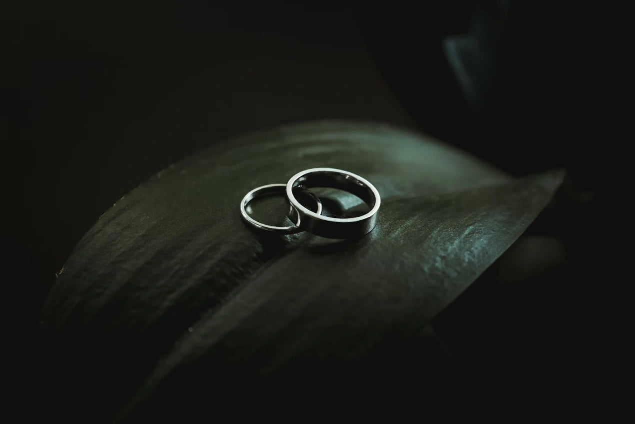 Two engagement rings placed on a leaf with a dark background