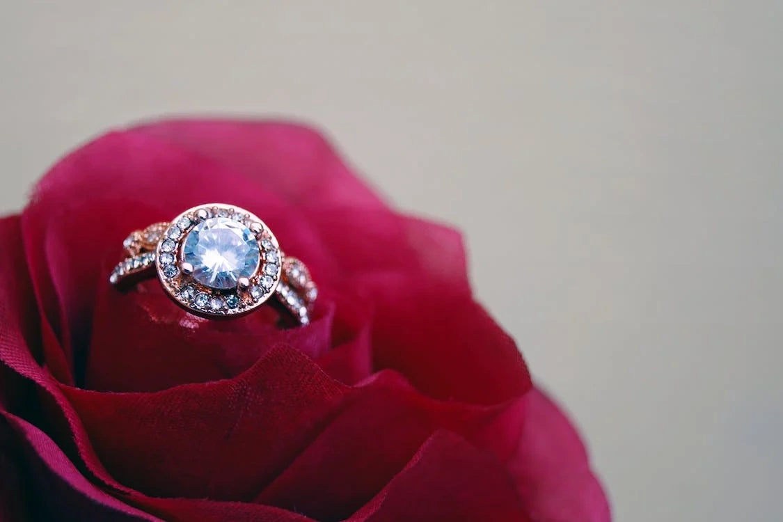 A beautiful diamond engagement ring placed on a glamorous red rosed