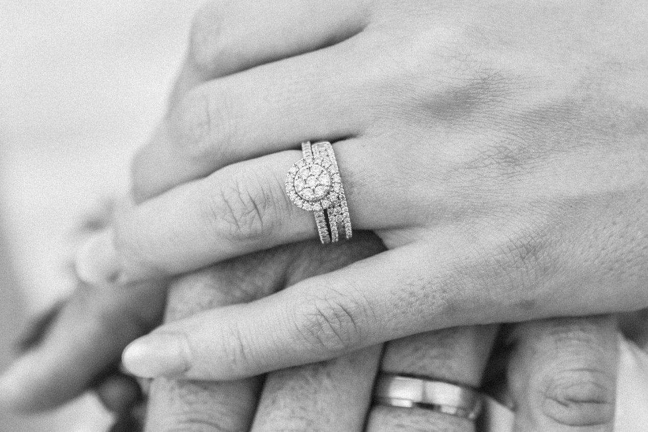 Two black and white colored hands with engagement rings