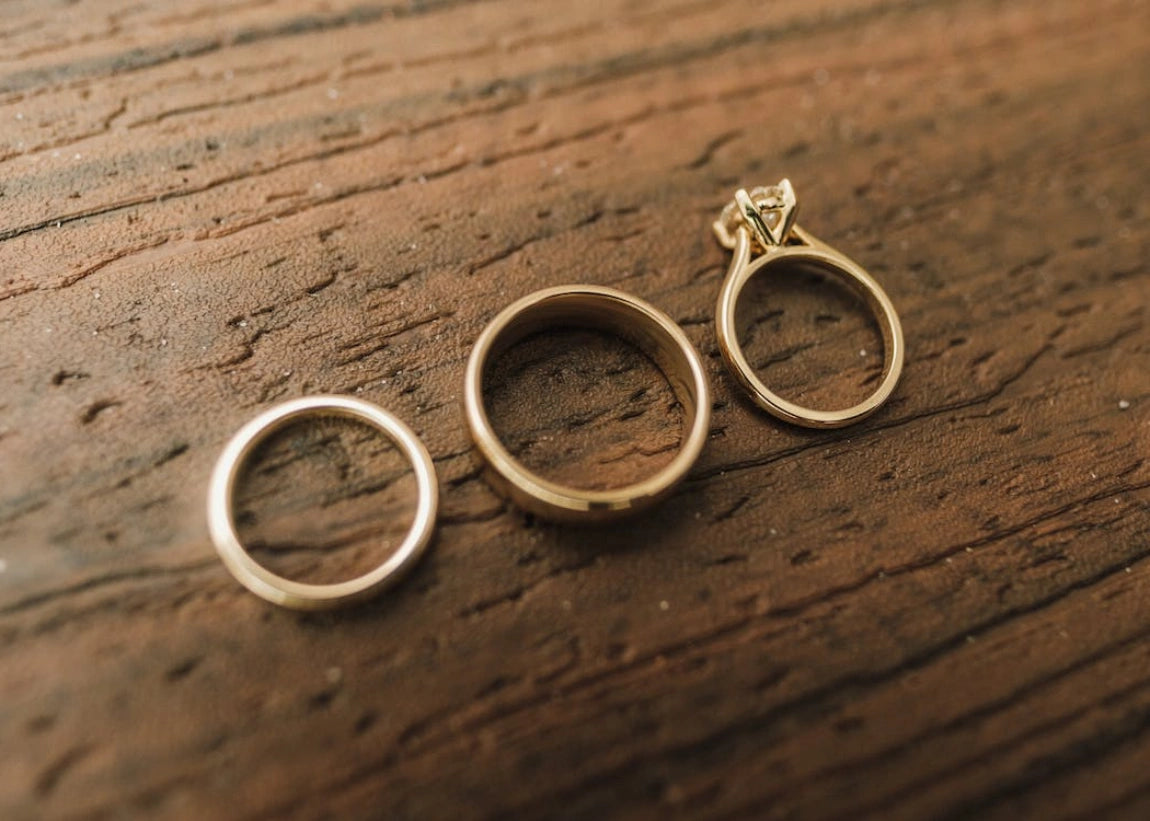 Three gold rings on a wooden surface