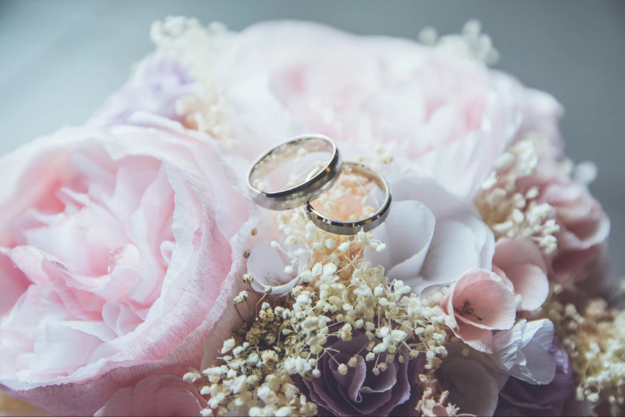 Gold-colored bridal ring on pink rose flower bouquet