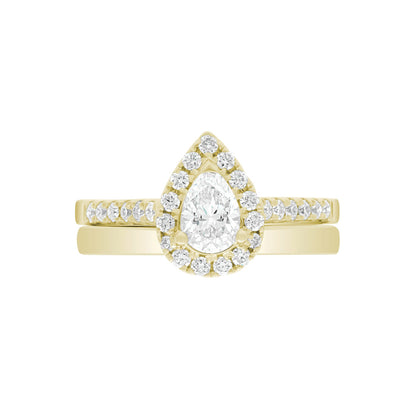 Pear Cut Halo Ring in yellow gold, laying flat with a matching yellow gold wedding band,on A WHITE SURFACE WITH A WHITE BACKGROUND